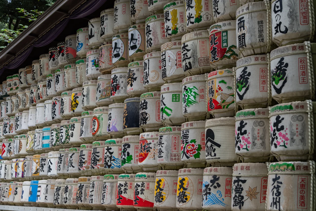 Mur de tonneaux de saké empilés, décorés de calligraphies colorées.