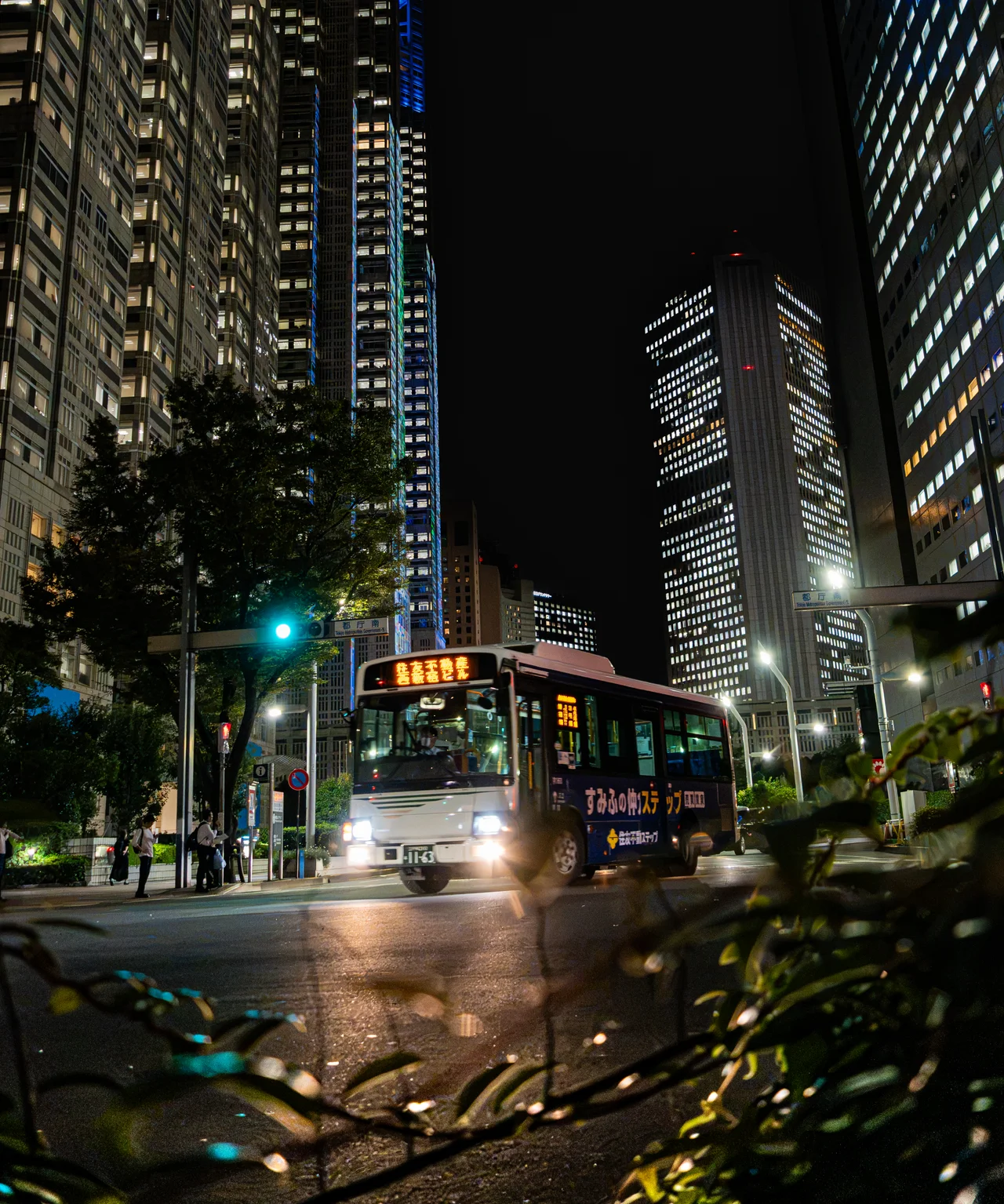 Un bus éclairé roule de nuit au pied de tours de bureaux.