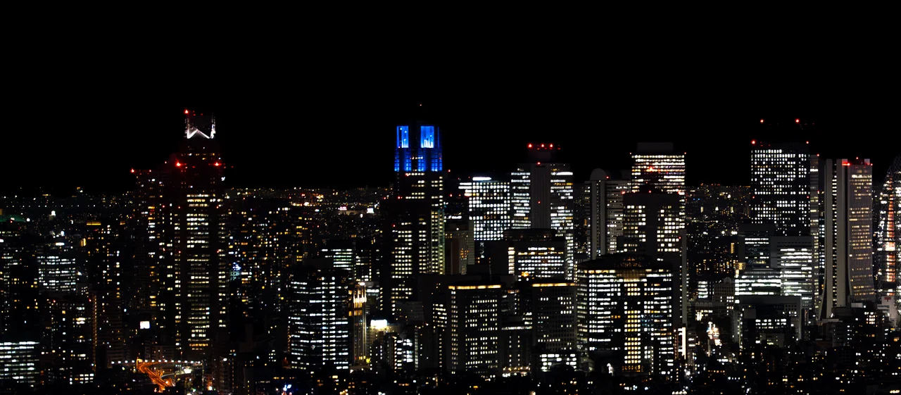 Panorama nocturne des gratte-ciel de Tokyo, fenêtres éclairées sur un ciel noir.
